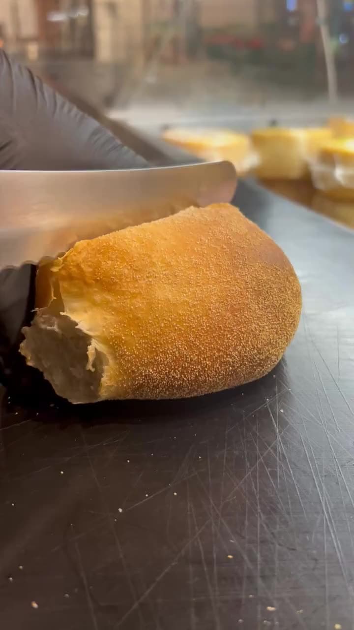 Ett nybakat, gyllenbrunt bröd skärs upp på disken.