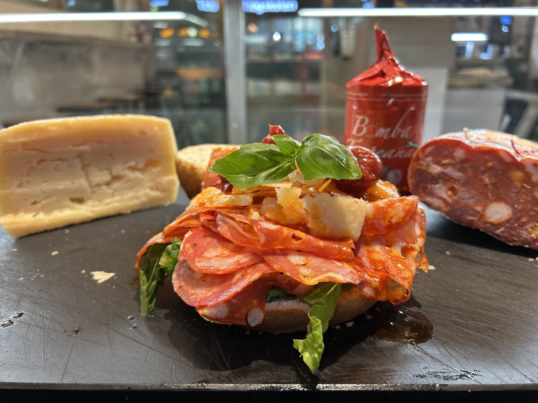 Flera färdiga rundsmörgåsar med skinka, mozzarella och basilika uppradade på disken.